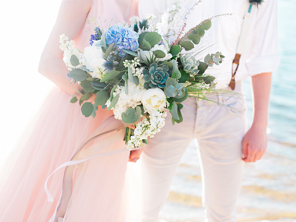 Beach wedding featuring dusty rose and emerald green florals