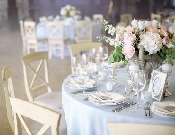 Dusty blue rustic wedding reception inside barn with place setting and floral centerpiece