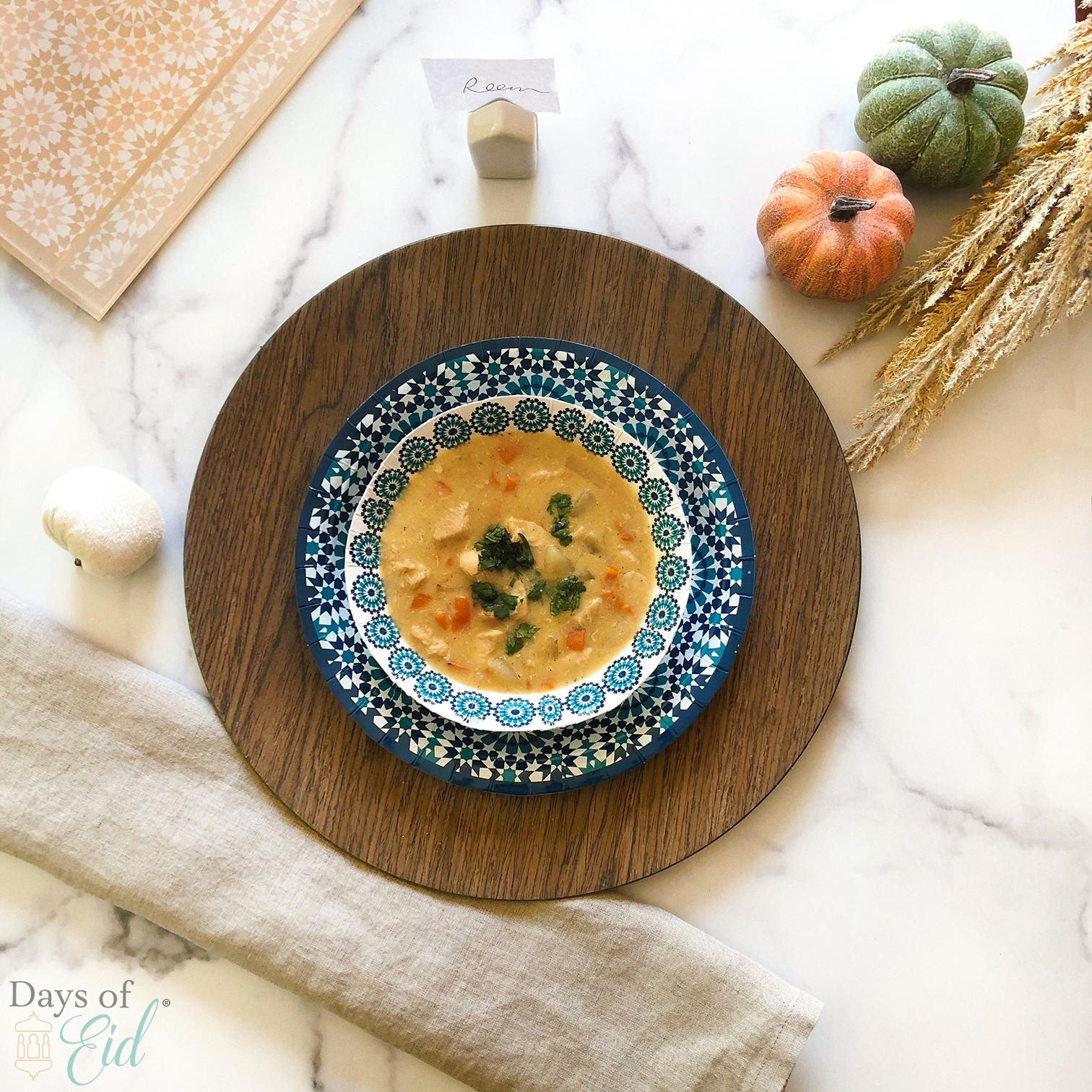 Bowl of soup plated next to linen napkin and pumpkins