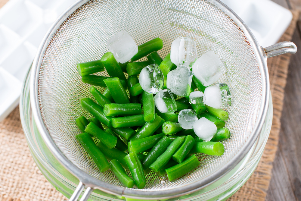 Shocking green beans with ice water for freezing