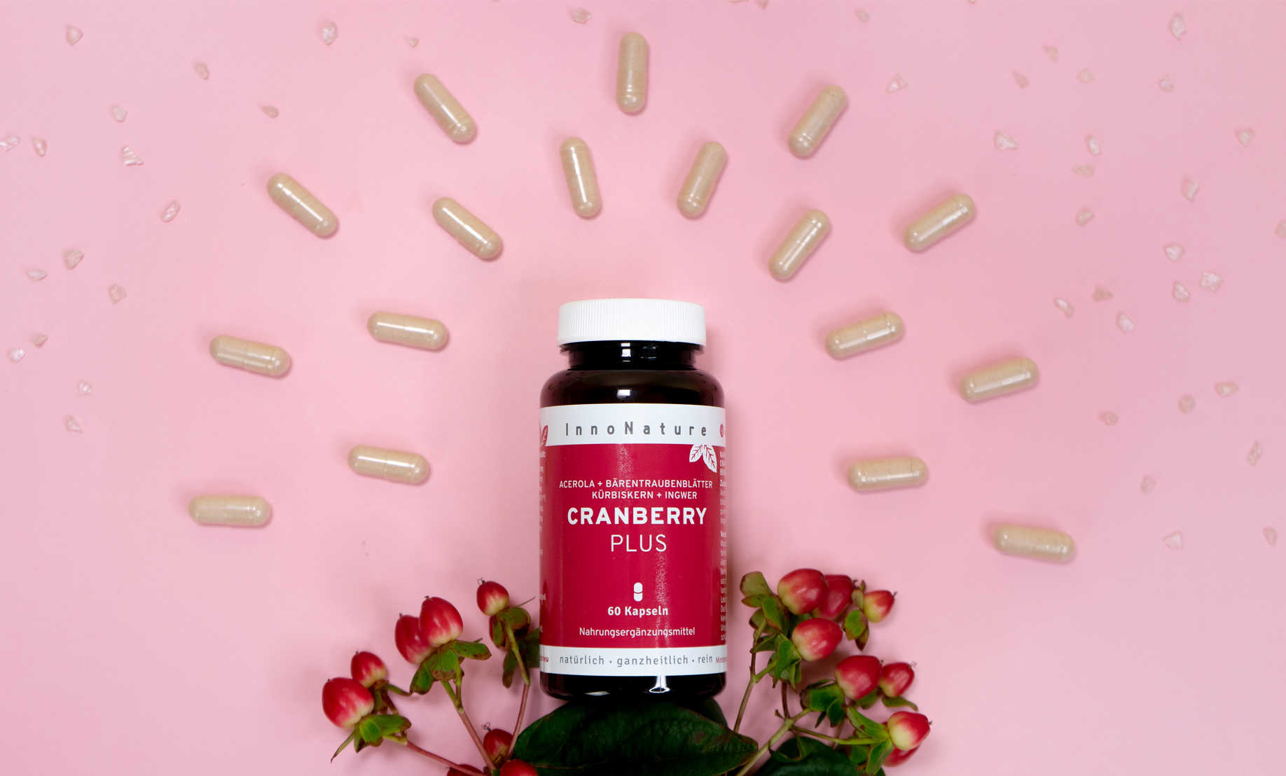 dose innonature cranberry plus auf rosa untergrund. kapseln und blumen liegen drum herum.