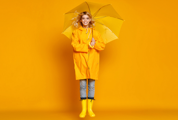 blonde-frau-mit-gelben-regenschirm-und-gelben-gummistiefeln-huepft-lachend-hoch