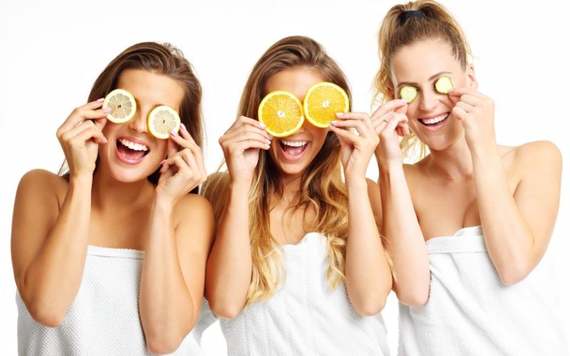 Drei Frauen mit Zitronenscheiben, Orangenscheiben und Gurkenscheiben vor den Augen.