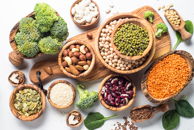 unterschiedliche-protein-und-vitamin-quellen-nüsse-linsen-brokkoli-in-schaelchen-auf-einem-holzbrett