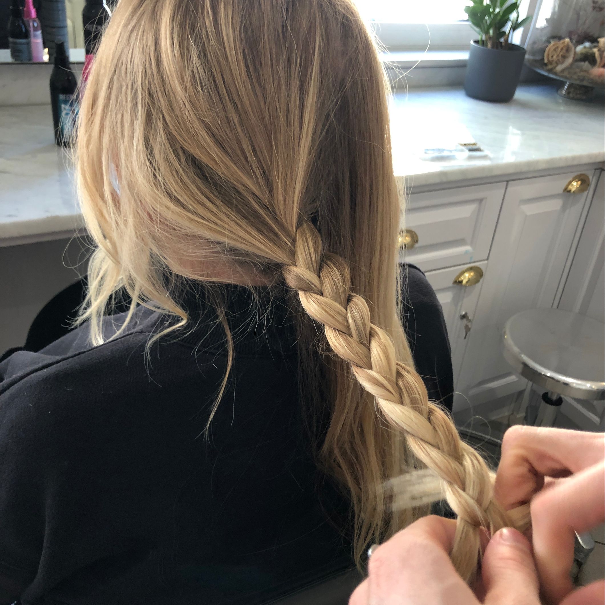 A woman is getting her hair braided in a salon - Josh Wood Hair Colour Expert