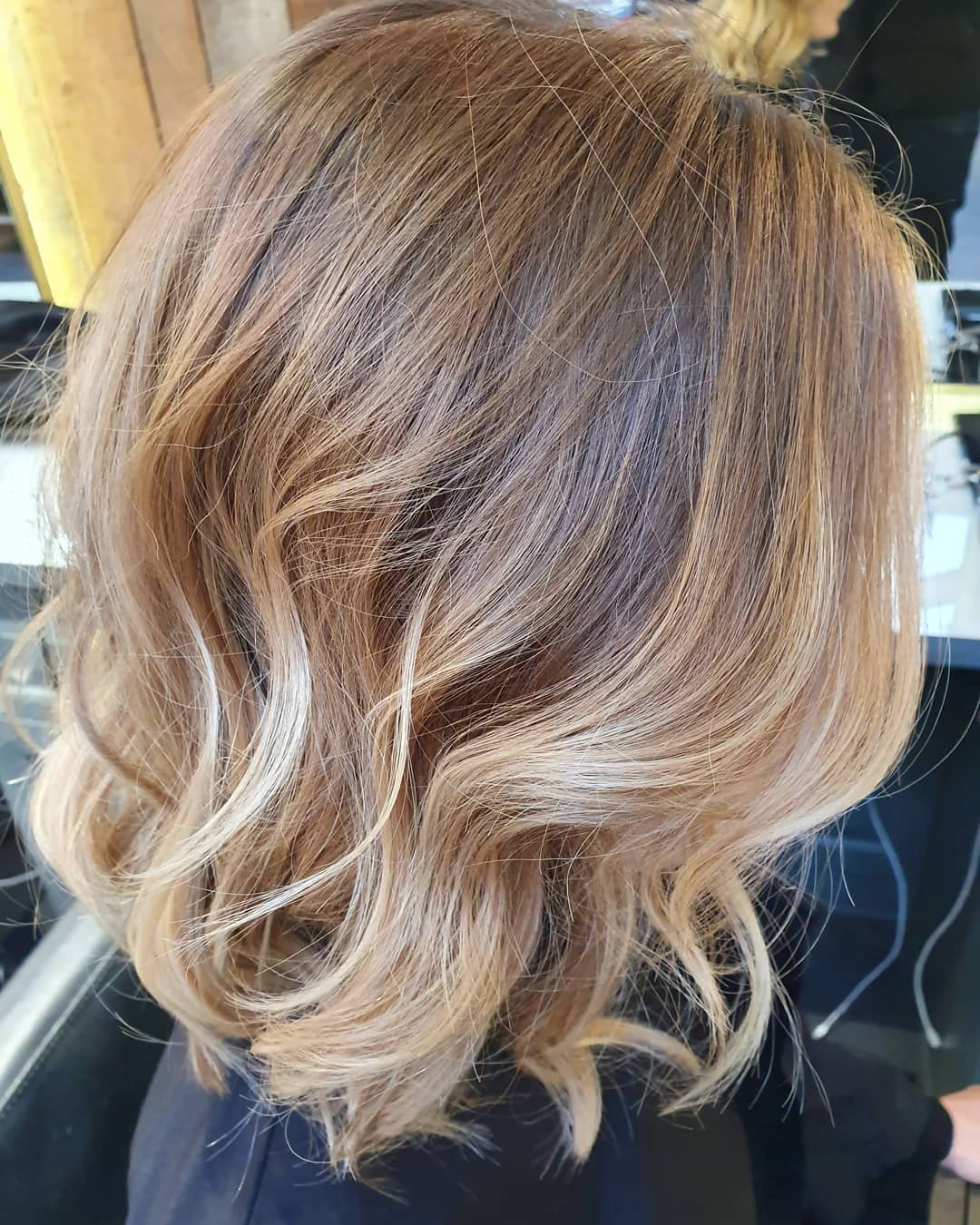 The back of a woman's hair with blonde highlights and a wavy bob - Josh Wood Hair Colour Expert