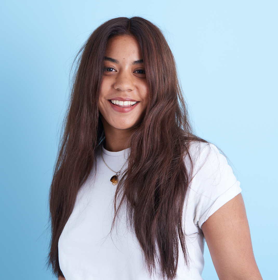 A woman wearing a white t - shirt smiling against a blue background - Josh Wood Hair Colour Expert