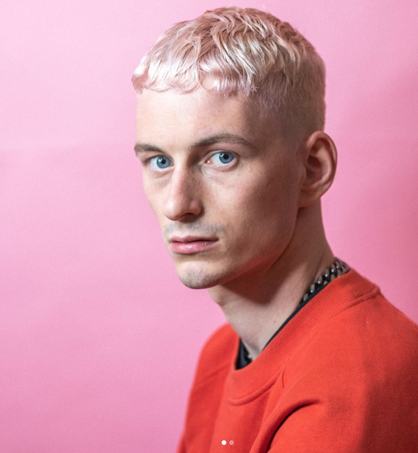 A man in a red sweatshirt with pink hair - Josh Wood Hair Colour Expert