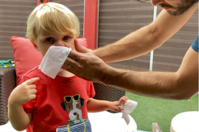 Father wipes toddler’s face with wet wipe