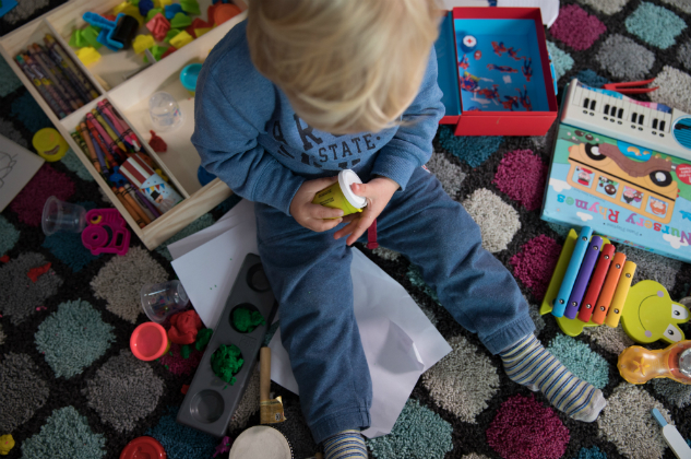 A little boy sits surrounded by toys