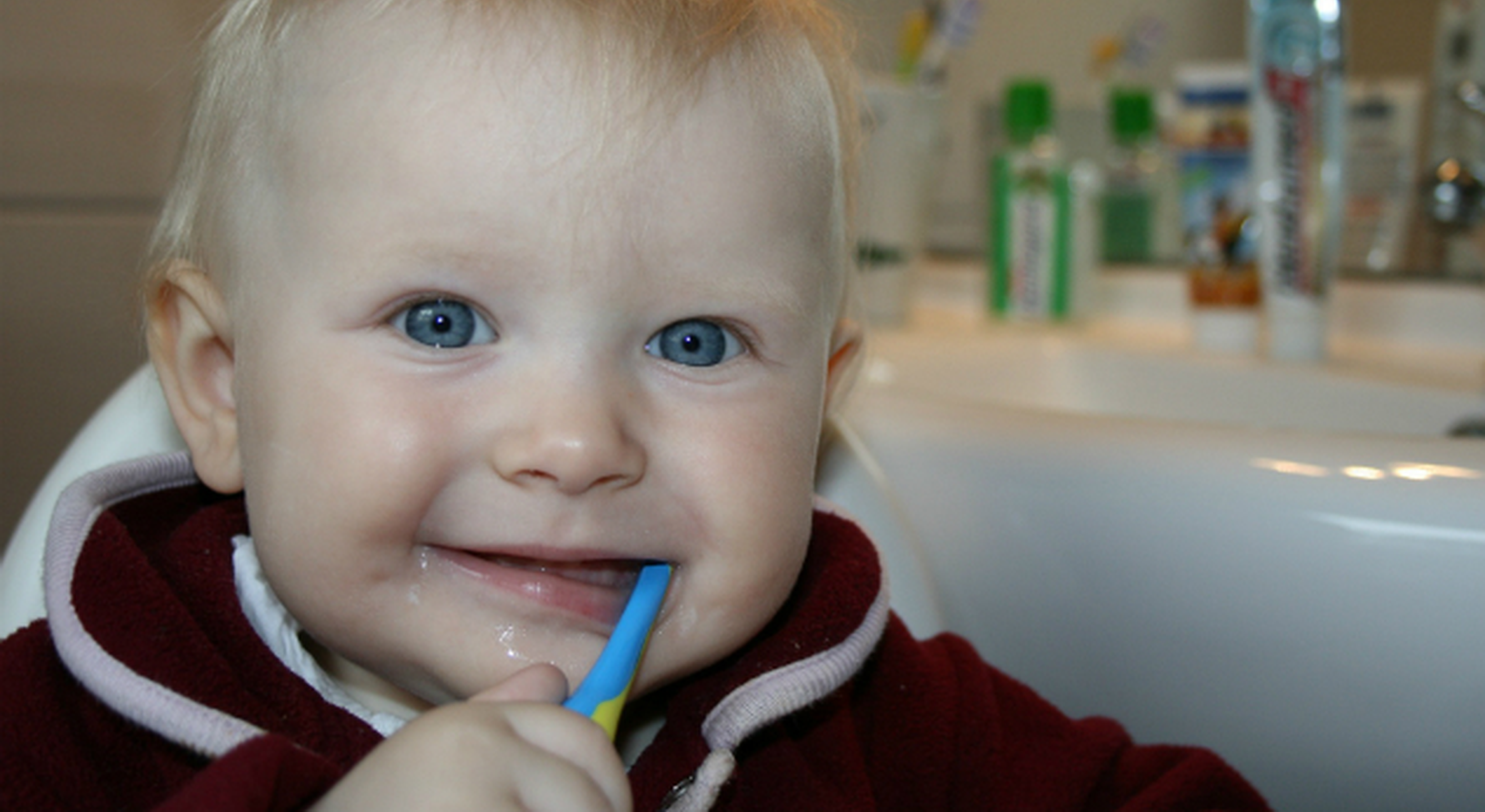 Smiling toddler brushing his teeth
