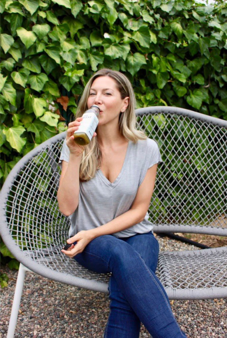 woman drinking bottle of cold pressed green juice (Note: Intentionally omitted the hyphen)